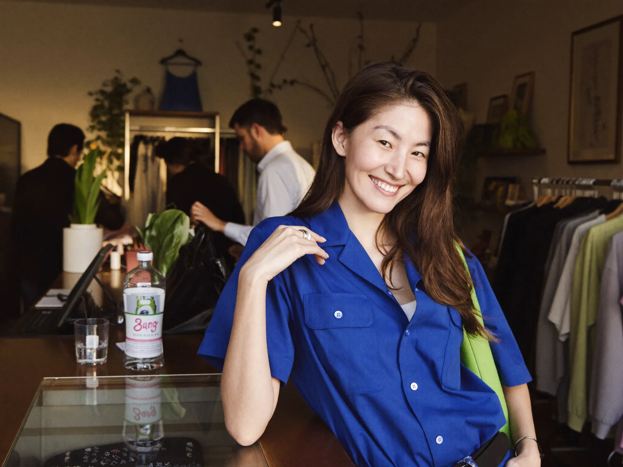 A shop owner at her counter, customers browsing behind her